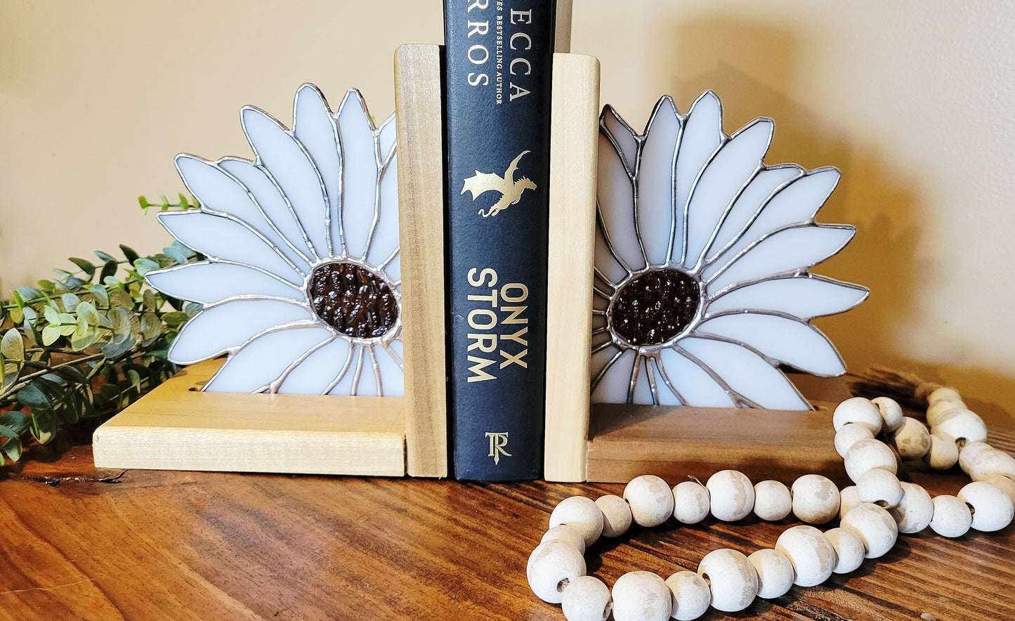 Pair of stained glass daisy bookends displayed on shelf with books and decor