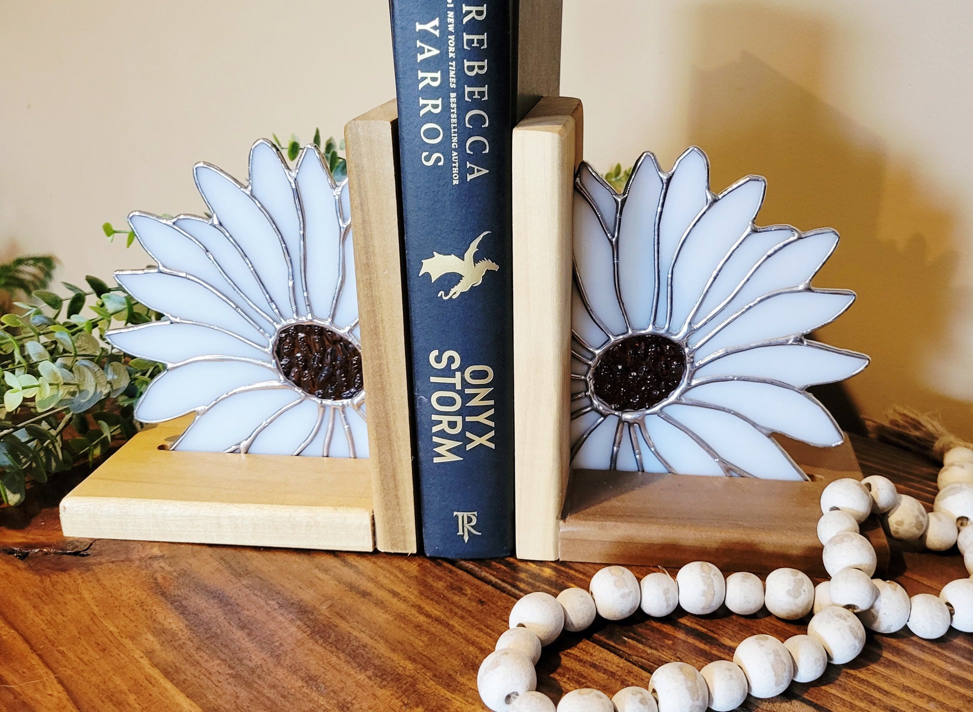 Stained glass daisy bookends with white petals and dark textured center on wooden bases holding books
